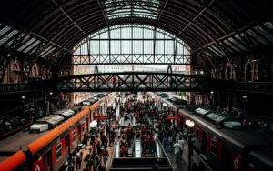 A bustling scene of people at a historic train station with arched roof and platforms.